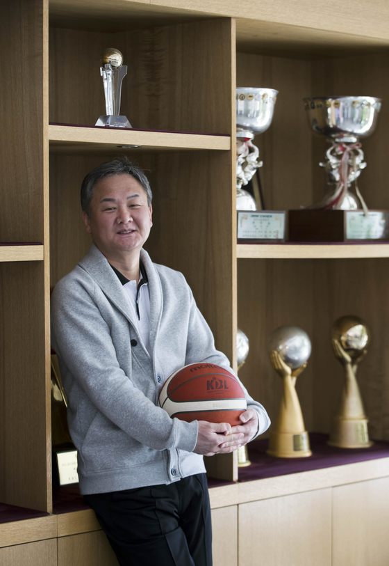 Ulsan Hyundai Mobis Phoebus's head coach Yoo Jae-hak poses for a photo in front of the Phoebus's championship trophies, located at the entrance of its training site in Yongin, Gyeonggi, on April 23. [KIM SUNG-RYONG]