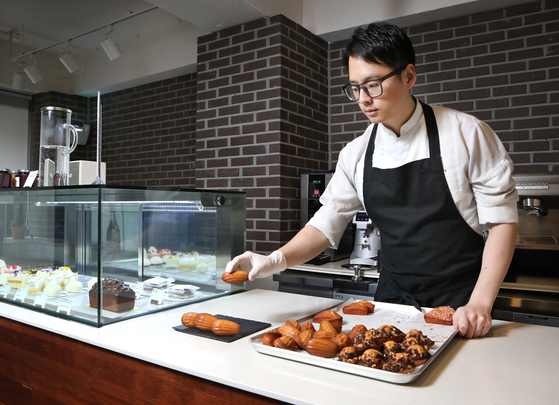 Pastry chef Choi Kyu-sung of Cedrat in Gangnam District, southern Seoul, puts out fresh baked madeleines in the morning before the store opens. [PARK SANG-MOON] 
