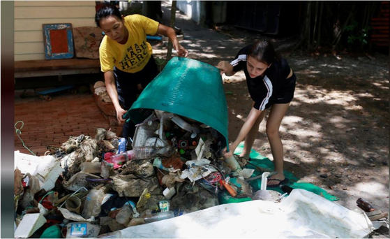 Thailand's former national windsurfer Amara Wichthong and her daughter collect rubbish near Pattaya beach at Chonburi, Thailand on May 12. [REUTERS/YONHAP]