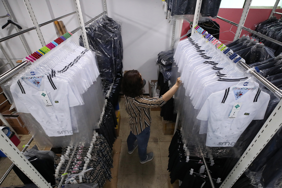A store employee organizes high school summer uniforms at Smart School Uniform’s Songpa branch in southern Seoul on Monday. High school seniors return to school this Wednesday after the long wait due to the coronavirus outbreak. [YONHAP]
