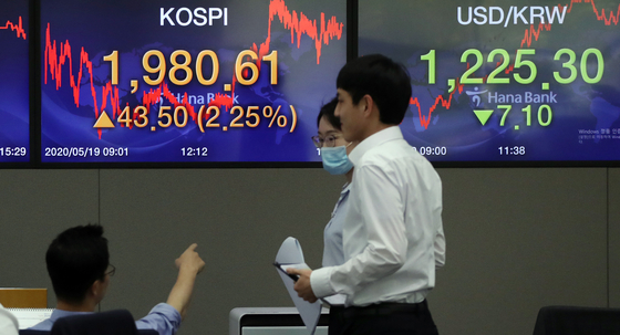 Employees walk pass the screen in the dealing room of Hana Bank in Jung-district, central Seoul, Tuesday. [YONHAP]