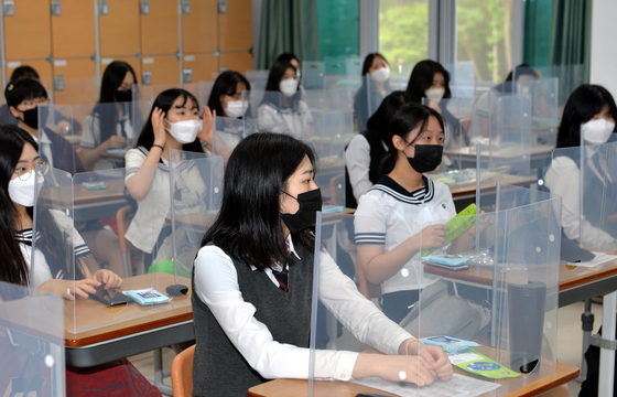 Seniors at Jeonmin High School in Daejeon sit at desks with plastic dividers on Wednesday. Schools reopened for the first time for high school seniors Wednesday since the coronavirus pandemic. [KIM SEONG-TAE]