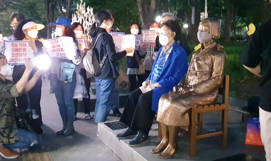 Lee Yong-soo, a ’comfort woman“ survivor and activist, sits next to a bronze statue symbolizing victims of Japanese wartime sexual slavery after making a surprise appearance at a weekly rally calling for a resolution to the issue in Daegu Wednesday evening. [YONHAP]