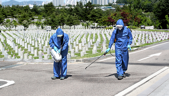 Workers at Seoul National Cemetery in Dongjak District, southern Seoul, carry out disinfection work Monday. Health officials last week re-closed all public facilities in Seoul, Incheon and Gyeonggi until June 14 to stem the spread of the coronavirus after a major cluster emerged at Coupang's distribution center in Bucheon, Gyeonggi. [YONHAP]  