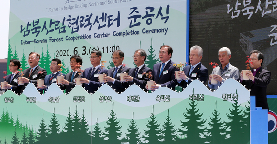 Unification Minister Kim Yeon-chul, fifthfrom left, and dignitaries celebrate the completion of an inter-Koreancooperation center on forestry in Paju, Gyeonggi, on Wednesday. [KIMSEONG-RYONG]
