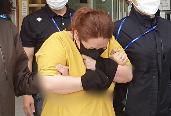 A 43-year stepmother, charged in the death of her nine-year-old stepson after allegedly locking him in a suitcase for seven hours, walks out of the Cheonan Dongnam Police Precinct after being questioned by investigators on Wednesday.  [NEWS1]
