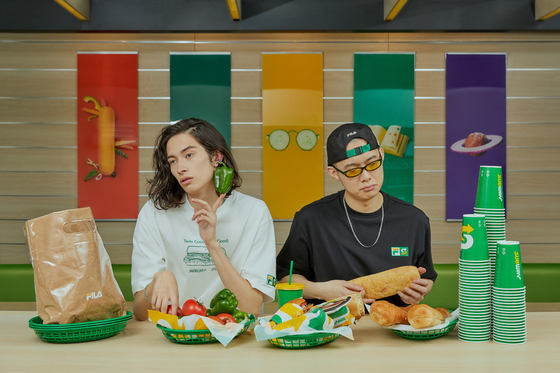 Models wear Subway-inspired clothes and eat sandwiches inside a Subway store. [FILA]