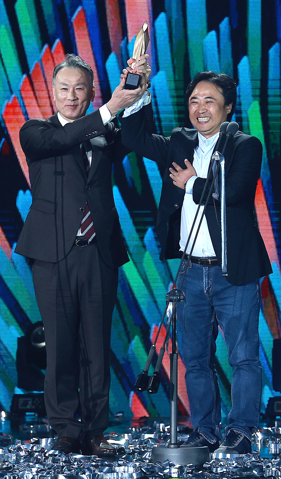 Vice president of the Pan Entertainment drama production company, left, and producer Yoon Jae-hyuk hold out their trophy in victory after their drama series "When the Camellia Blooms" received the Grand Prize. 