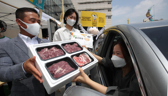 Park Dae-an, chairperson of a committee promoting the development of the meat industry, delivers a box of meat to a citizen at Bitplex mall’s drive-thru parking lot in Wangsimni, eastern Seoul, during the "2020 Untact Meat Day" event on Sunday. [YONHAP]