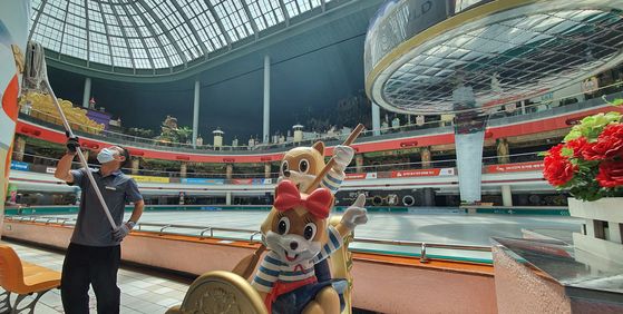 An employee cleans a pillar at Lotte World, located in Jamsil, western Seoul, Monday. The indoor theme park was closed Sunday after health authorities confirmed a coronavirus patient had visited the entertainment facility. It will reopen Tuesday. [YONHAP]
