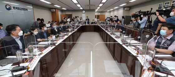 The Minimum Wage Commission meets in Sejong, Thursday, for the initial meeting to decide on next year's minimum wage. A transparent wall was put up between participants to prevent infections. The minimum wage is updated on an annual basis, and currently stands at 8,590 won ($7.22) per hour. [YONHAP] 