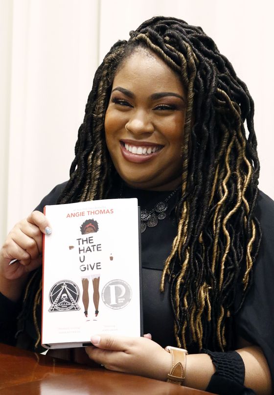 In this Oct. 10, 2018 photograph, author Angie Thomas holds a copy of her novel, "The Hate U Give," at a book signing in Jackson, Miss. Thomas' best-selling novel about a black teen murdered by police was adapted into a feature film of the same name. [AP]
