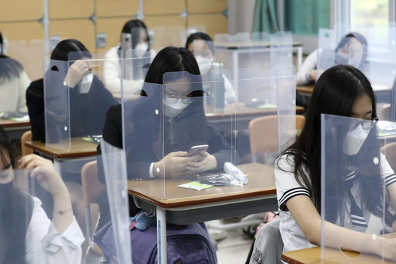Senior students wait for class to begin with plastic boards placed on their desks at Jeonmin High School in Daejeon on May 20, as schools started reopening for high school seniors that week. It was their first day of class in the Spring semester, originally scheduled to begin in March. [AP/YONHAP]
