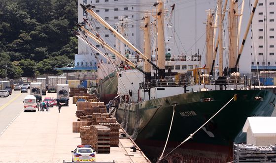 Crew members of the Russian-flagged Ice Stream disembark from the cargo ship Tuesday at Gamcheon Port in Busan to be transferred to Busan Medical Center for Covid-19 treatment. Out of 21 members, at least 16 tested positive Monday. [NEWS1]