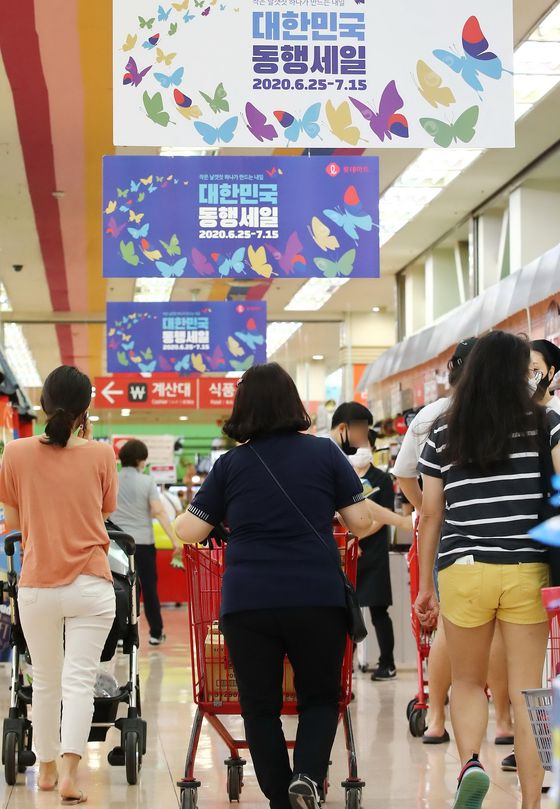 Customers shop at a discount store Thursday, a day before the start of the summer blowout sale that runs from Friday to July 15, which was planned by the government to help Korean retailers make up for the losses from the coronavirus pandemic during the first half of the year. Major retailers have been distributing discount coupons a day before the event. [YONHAP]   