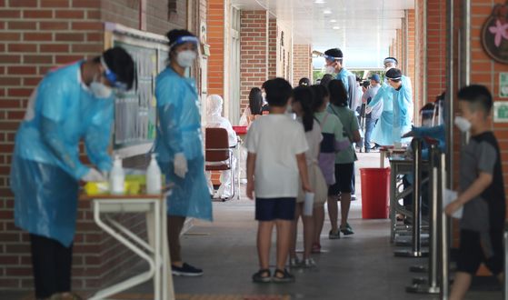 Students of Mukhyeon Elementary School in Jungnang District, eastern Seoul, wait in line at the school to get tested for Covid-19 on Sunday. One student of the school tested positive on Saturday. [YONHAP]