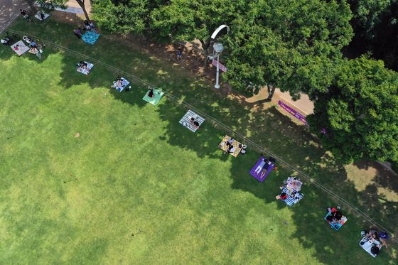 People lie on picnic blankets at a park in Seo District, Daegu, enjoying the summer weather Sunday while keeping two meters apart from each other in line with coronavirus social distancing precautions. [YONHAP]