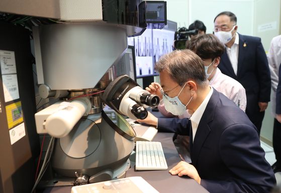President Moon Jae-in examines the purity of hydrogen fluoride gas though a electron microscopic on Thursday at SK hynix's plant in Icheon, Gyeonggi. [YONHAP]
