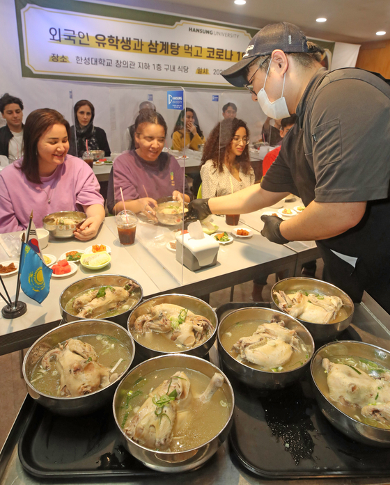 International students try samgyetang, a traditional chicken soup with ginseng, at an event to celebrate Chobok, the first day of the year’s hottest season according to the Korean calendar, at Hansung University in Seongbuk District, central Seoul, on Monday. Samgyetang is commonly eaten by Koreans to beat the heat. This year, Chobok falls on Thursday. [YONHAP]