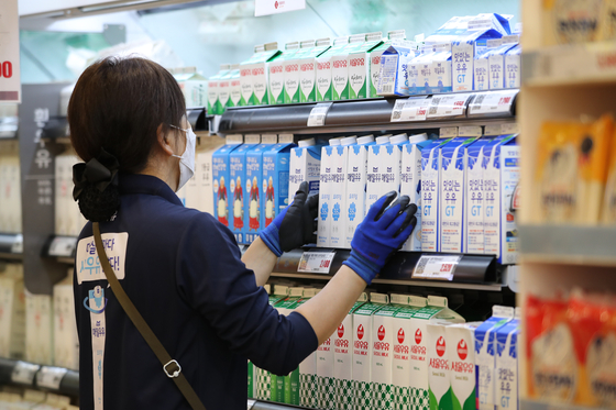 An employee organizes cartons of milk on the shelves of a discount store in Seoul Wednesday after the dairy industry decided to freeze raw milk prices, which determine the price of dairy products, to ease the economic impact from the coronavirus pandemic. Prices of a liter of raw milk, which is determined every two years, will stay the same until next August when a 21 won increase per liter kicks in. [YONHAP] 