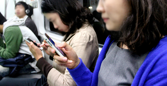Passengers on the subway enjoy contents through their smartphones. [JOONGANG ILBO]