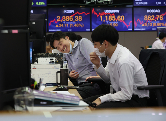 Stock traders smile with joy on Monday at a trading room in Hana Bank, in Jung District, central Seoul. The Kospi continued to hit record highs for five consecutive trading sessions, closing 1.48 percent higher than the previous session at 2,386.38 points, the highest since June 15, 2018. [YONHAP]