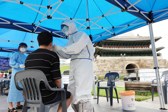 Health officials examine a man at a makeshift Covid-19 testing site at Namdaemun Market in Jung District, central Seoul, on Monday. Anyone who visited the market’s Kennedy Complex from July 30 to Aug. 8 has been strongly recommended to be tested. [YONHAP]