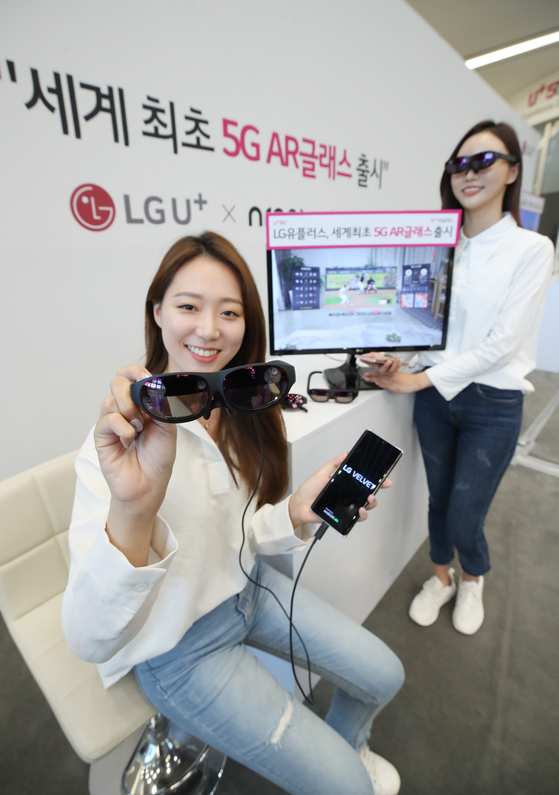 Models pose with LG U+'s 5G Augmented Reality glasses at the telecom company's headquarters in Yongsan, central Seoul, on Tuesday. LG U+'s Real Glass is a wearable device allowing users to view content superimposed on the real world through its lenses. [YONHAP]