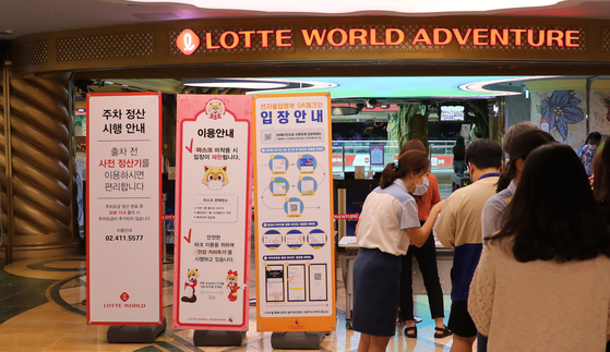 Lotte World employee checks the temperature of visitors to the amusement park in Jamsil, southern Seoul, on Monday. Lotte World was closed on Sunday after a visitor infected with the coronavirus was found to have visited the amusement park on Saturday. [YONHAP]