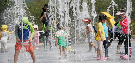 Children play in a fountain to cool themselves off in Ulsan on Monday, as a heat wave hits much of the country. [NEWS1]