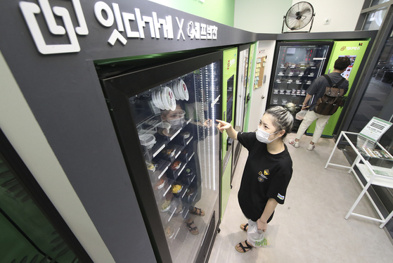 A customer uses a vending machine at a 24-hour unmanned store that sells side dishes in Magok in Gangseo District, western Seoul, on Tuesday. The store uses KT’s Giga energy manager franchise plus solution service. The service maximizes the energy efficiency of unmanned stores, including allowing remote control via mobile device, and provides real-time energy related information to the store owner. [KT]