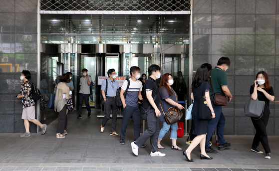 Civil servants at the main Seoul City Hall building in Jung District, central Seoul, evacuate Wednesday afternoon after a worker on the second floor tested positive for the coronavirus. [YONHAP]