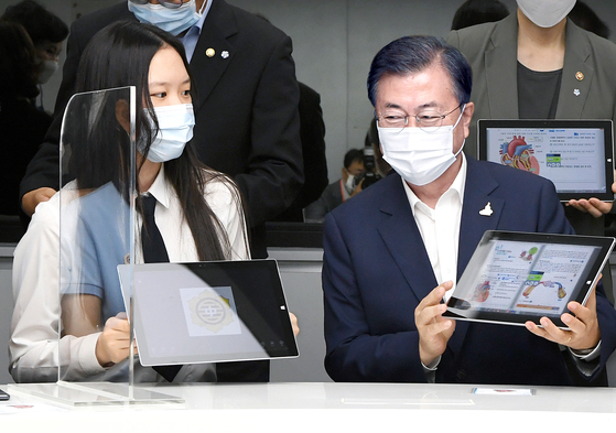  President Moon Jae-in talks with a student at Changdeok Middle School in central Seoul on Tuesday. When a teacher asked him what he wondered most about the future, Moon immediately replied, ’real estate.“ [JOINT PRESS CORPS]
