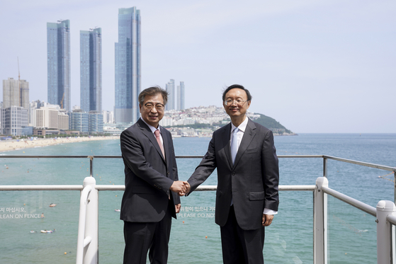 Suh Hoon, left, director of the Blue House National Security Office, and Yang Jiechi, a member of the Political Bureau of the Communist Party of China's Central Committee, shake hands in front of Haeundae Beach after talks at the Westin Chosun Hotel in Busan on Saturday. [JOINT PRESS CORPS]