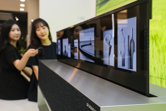 Employees demonstrate LG Electronics' rollable TV at Hyundai Department Store's Mokdong branch in Yangcheon District, western Seoul, on Wednesday. Visitors to the store can look at the world's first rollable TV and make orders from mid-September through the company's advance reservation system. [NEWS1] 