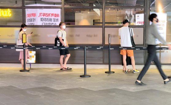 Customers keep a distance while waiting for a seat at a restaurant in Seoul on Monday. As the number of new cases continues to remain above 200, stricter social distancing regulations have been implemented. [YONHAP]