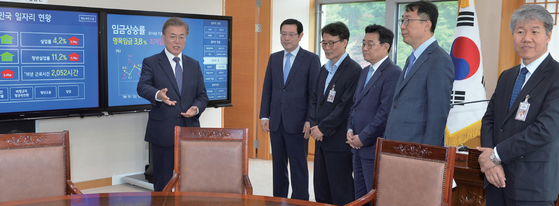 President Moon Jae-in converses with his aides in front of the electronic bulletin board on jobs in his office on Jan. 20, 2018, eight months after coming into office.