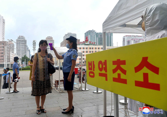 A health official conducts a temperature check on a citizen at the entrance of a train station at North Korea's capital of Pyongyang on Saturday, according to a photograph released by state media. [YONHAP]