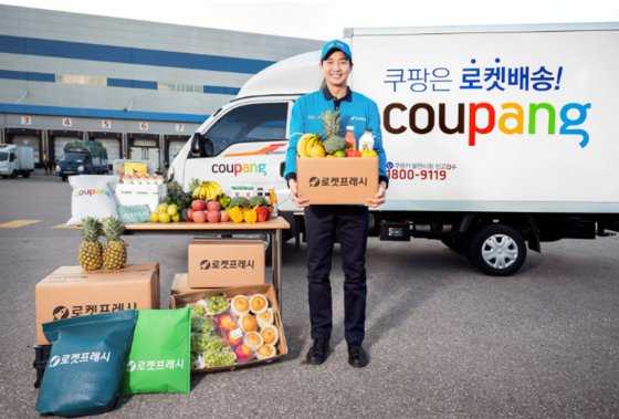 A Coupang Rocket Fresh delivery man stands in front of the company’s delivery vehicle. [JOONGANG PHOTO]