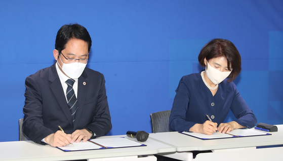 President Choi Dae-zip of the KMA, left, and Rep. Han Jeoung-ae, chief policymaker of the Democratic Party (DP), sign an agreement on Friday.  [YONHAP] 