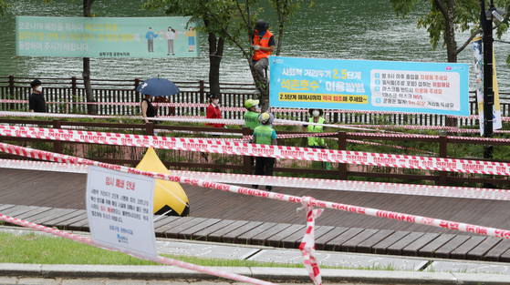 Officials limit access to parts of Seokchon Lake Park in Songpa District, southern Seoul, Friday, as Level 2.5 social distancing measures extend to a second weekend. [NEWS1]