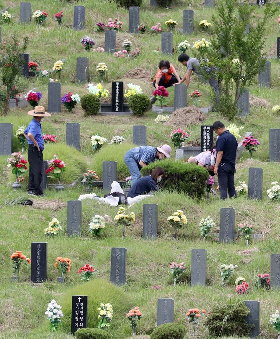 People tidy up the graves of their ancestors in a cemetery in Busan on Sunday, ahead of the Chuseok holiday, which falls on Oct. 1 this year. [YONHAP]