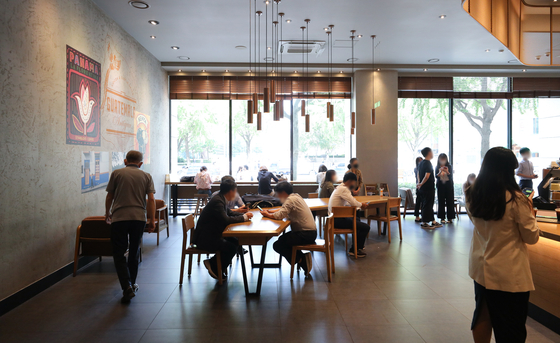 Customers return to a coffee shop chain in downtown Seoul on Monday, the first day after the so-called Level 2.5 social distancing measures were lifted for the greater Seoul area. [NEWS1]