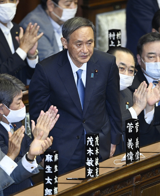 Yoshihide Suga, center, stands after being elected Japan's new prime minister in Tokyo on Wednesday. Suga, the new leader of the ruling Liberal Democratic Party, was chosen to succeed Shinzo Abe in an extraordinary parliamentary session on Wednesday. [YONHAP]