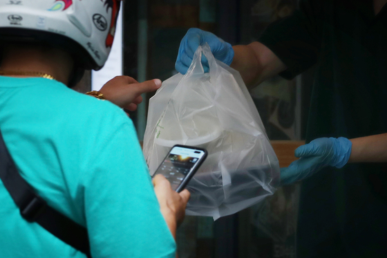 A delivery rider delivers a packaged meal to a customer last month. As social distancing continues, the number of online transactions for food delivery has skyrocketed over recent months. [YONHAP]