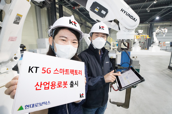 KT employees pose beside the "5G Smart Factory Industrial Robot" at Hyundai Robotics' showroom in Gwangju, Gyeonggi. [KT]