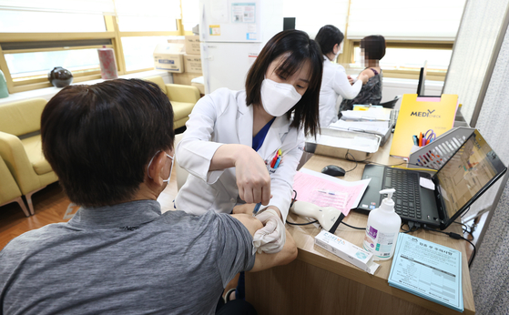 A doctor at the Gangnam branch of the Korea Association of Health Promotion in Songpa District of southern Seoul gives an influenza shot to a patient on Monday.  [YONHAP] 
