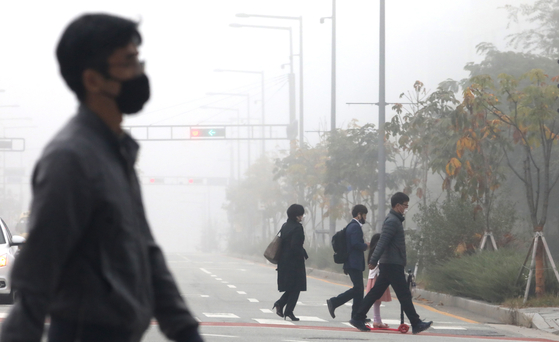 Commuters walk through smog on Tuesday as the comprehensive air quality index reached "bad" levels in Sejong. [NEWS1]