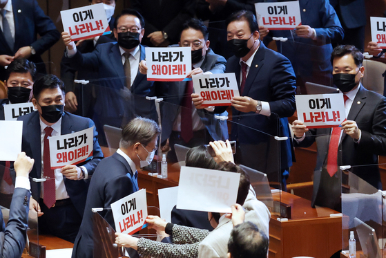 As President Moon Jae-in leaves the main hall of the National Assembly after delivering the 2021 budget speech, lawmakers of the opposition People Power Party show him protesting signs, asking "What happened to this country?" on Wednesday. [YONHAP]