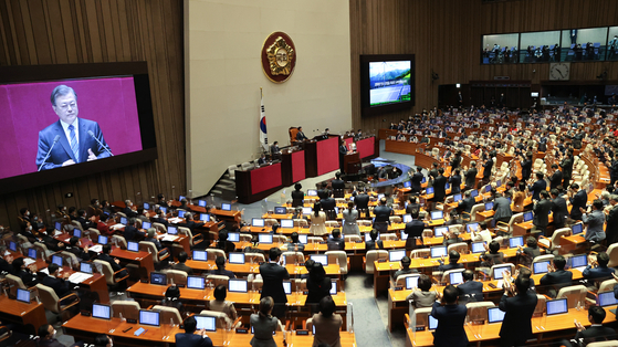 President Moon Jae-in receives a standing ovation from ruling Democratic Party lawmakers Wednesday after he announced a pledge to achieve net-zero carbon emissions by 2050. [YONHAP]